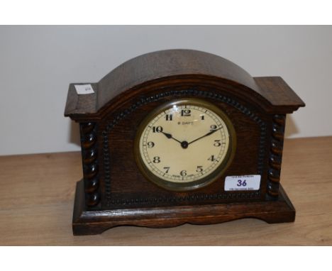An early 20th century oak mantle clock, having an enamelled Arabic dial, 8 day Swiss movement, and housed within a domed oak 