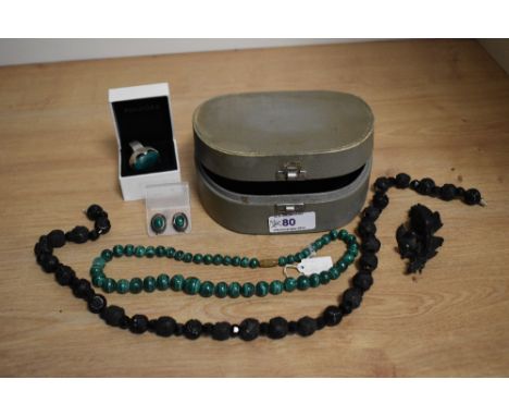 A vintage jewellery case containing a string of mourning beads, brooch, string of malachite beads and earrings and an Israeli