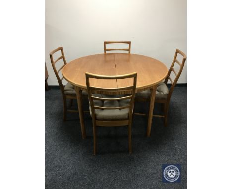 A 1970's circular teak extending dining table and four ladder back chairs 