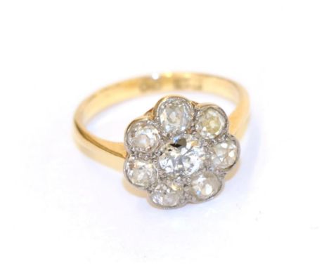 A diamond cluster ring, the central round brilliant cut diamond within a border of smaller old cut diamonds, in white claw an