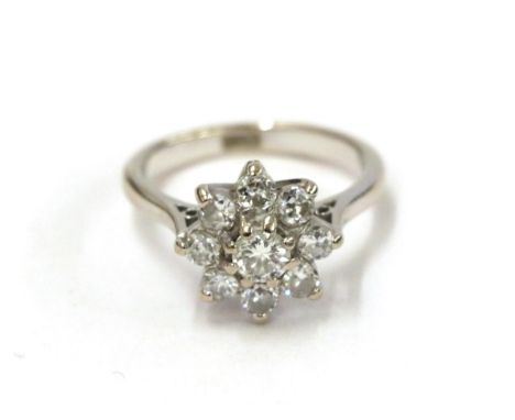 A diamond cluster ring, the round brilliant cut diamond within a border of smaller round brilliant cut diamonds, in white cla