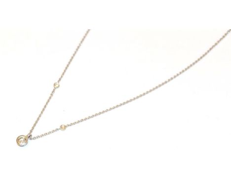 A diamond pendant on chain, the round brilliant cut diamond in a white rubbed over setting, on a fine trace link chain with t