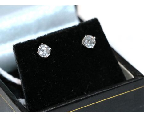 A pair of diamond solitaire earrings, the round brilliant cut diamonds in white four claw settings, total estimated diamond w