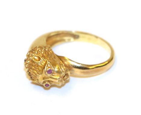 A lion mask ring, the lion mask motif with round cut ruby eyes in yellow collet settings, to a plain polished shank, finger s