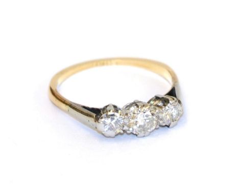 A diamond three stone ring, the graduated round brilliant cut diamonds in white claw settings, to a yellow tapered shoulder p