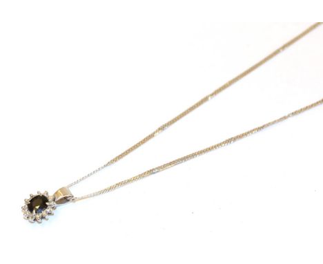 An 18 carat white gold sapphire and diamond cluster pendant on chain, the oval cut sapphire within a border of eight-cut diam
