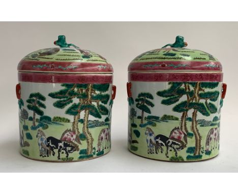 A pair of Chinese famille rose lidded pots depicting horses is a mountainous landscape, each with 4 handles in the form of br