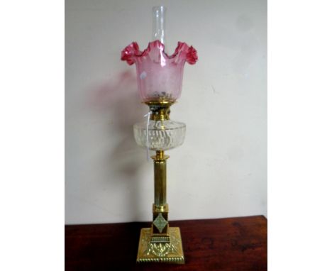 A 19th century brass Corinthian column oil lamp with etched glass cranberry shade, clear glass reservoir and chimney. Height 