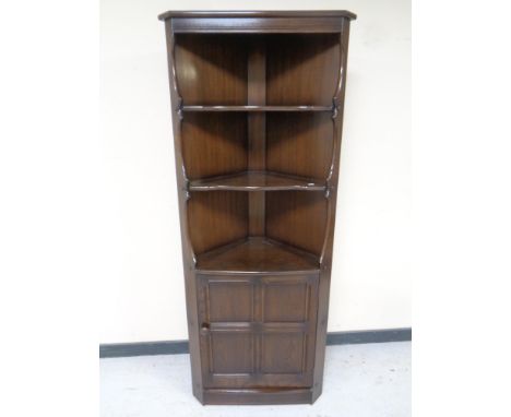 An Ercol elm and beech corner cupboard fitted shelves above