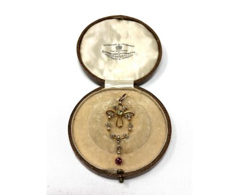 An Edwardian 9ct gold peridot, seed pearl and garnet pendant, the peridot set on a tied gold bow within a garland of seed pea