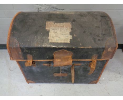 An antique leather bound dome topped trunk bearing railway luggage labels.