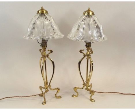 TABLE LAMPS.
A pair of early 20th century, Art Nouveau brass lamp bases with clear glass fluted shades. Height 54cm.