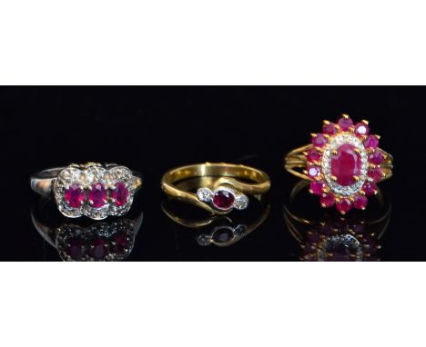 Two modern 9ct ruby and diamond cluster rings, together with an earlier 18ct three stone example. (3).