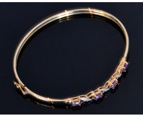A modern 9ct amethyst and diamond bangle four oval claw set amethyst stones spaced by diamonds. 
