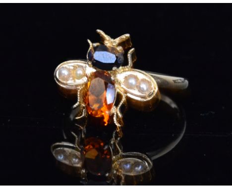 A 9ct hallmarked ring modelled as a bee with seed pearl set wings flanking citrene and sapphire set body, ring size O.
