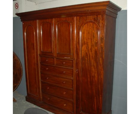 A Victorian mahogany compactum wardrobe, the centre section with three sliding trays over two short and four long drawers fla