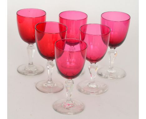 A set of six late 19th Century ruby bowl wine glasses with a clear crystal facet cut stem and circular spread foot, height 13