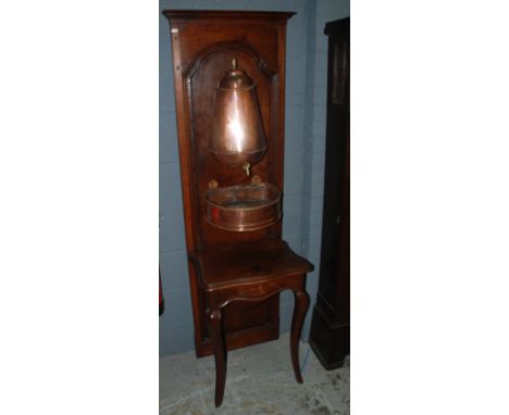 An early 20th Century French walnut washstand fitted with a copper samovar type dispenser over a hanging copper basin on shap