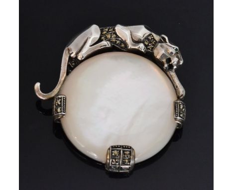 An Art Deco style sterling silver and mother of pearl panther brooch by Ari D Norman, the circular mother of pearl disc mount