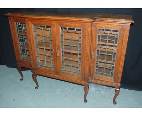 An Edwardian oak breakfront display cabinet enclosed by leaded light doors on cabriole legs, length 158cm