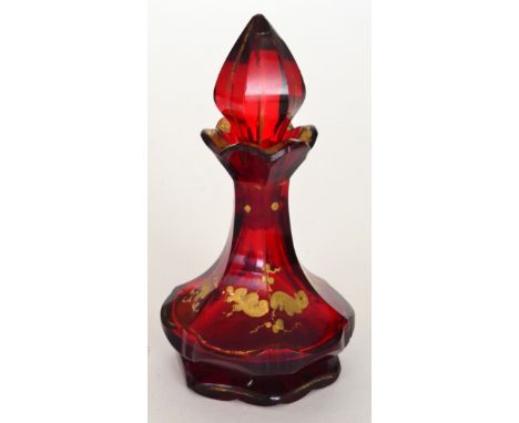 A 19th Century Bohemian scent bottle of low shouldered form with a slice cut body below a spire form stopper, gilt decorated 