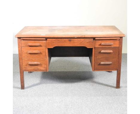 A mid 20th century light oak desk, containing seven short drawers136w x 76d x 73h cm