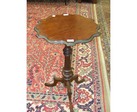 A mahogany and stained wood wine table the shaped circular top on turned column and tripod support, 48cm diameter.