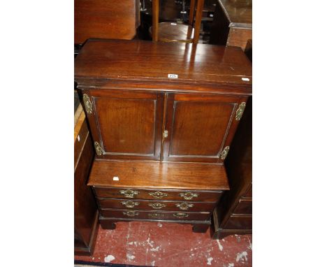 A George III miniature cabinet on chest, circa 1780 and later, the cabinet top with moulded cornice and pair of panel doors e