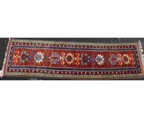 Turkish wool runner, the geometric motifs on red ground within polychrome borders, 298cm x 82cm. 