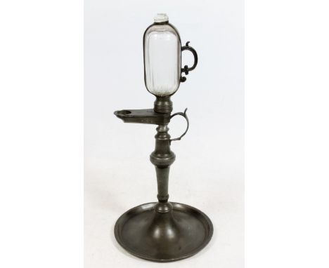 Continental pewter whale oil lamp clock, 19th century, the glass reservoir enclosed within pewter hour marked strap, protrudi
