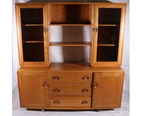 Ercol Windsor light elm modular sideboard/display cabinet, c1960s, of two glazed side cupboards with central shelf unit, on a