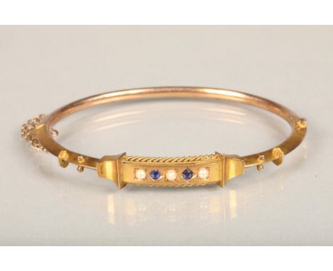 Victorian 9ct gold bangle set with sapphire and seed pearls, applied '9ct' lozenge to the reverse, 7.6g. 