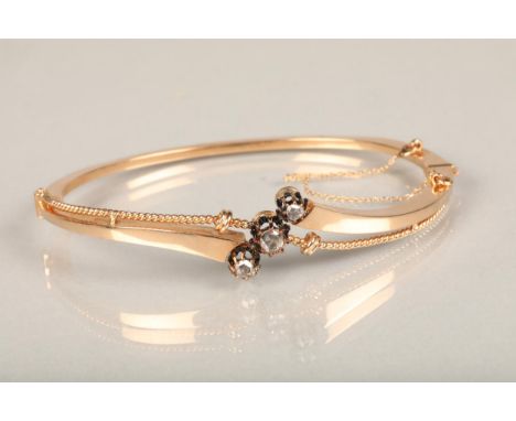 Yellow metal and three stone diamond bangle, the hinged bangle with twisted wirework frame set with three rose cut diamonds.&