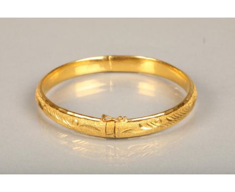 Chinese yellow gold bangle, the textured surface engraved with floral designs, internal W5.7cm, 21g, in original Chinese reta