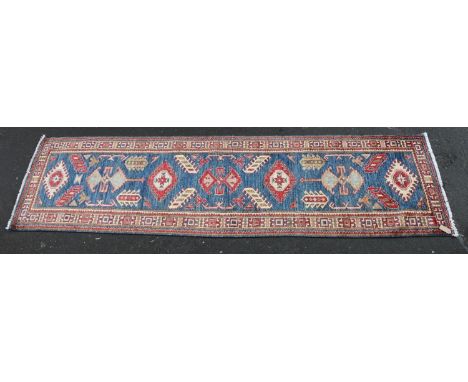 Caucasian style runner, the geometric designs on a blue ground within conforming polychrome border, 280cm x 80cm. 