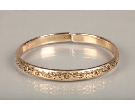 Rose gold coloured yellow metal West Indian bayras bangle with floral pattern, unhallmaked but typically 18ct gold, 37.4g gro