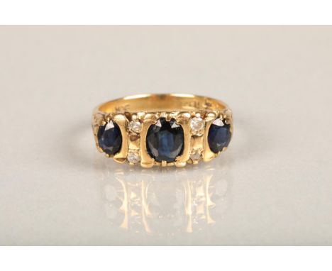 Early 20th century 18ct gold three stone sapphire and diamond ring, the oval sapphires interspaced with four small diamonds i