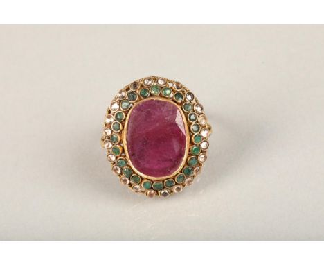 Indian ruby, emerald and white stone cluster cocktail ring (tests as gold), the large oval facet cut ruby encircled with halo