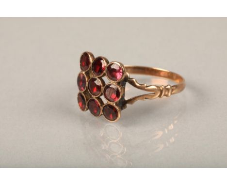 Edwardian garnet and yellow metal ring, the nine round cut garnets in grid shape on split shoulders leading to a plain band, 