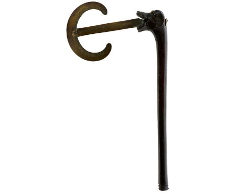 A 19TH CENTURY BENIN AXE, the crescent form brass head with incised geometric decoration, the wooden haft with carved mythica