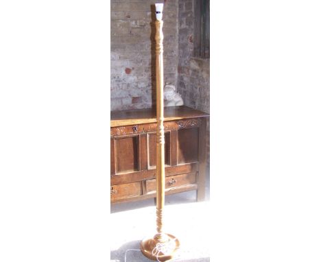 An oak turned column Standard Lamp with fringed shade and circular foot.