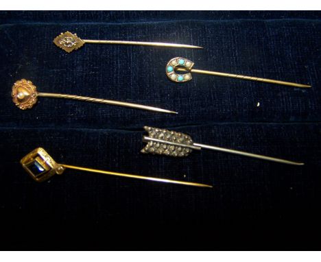 Two Stick Pins marked '15ct.' one set with a central split pearl, another stick pin set with blue paste and two others.