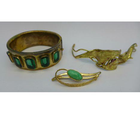 A plated bangle set with green glass stones, a yellow metal bangle and a brooch
