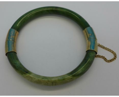 A jade bangle with yellow metal mounts