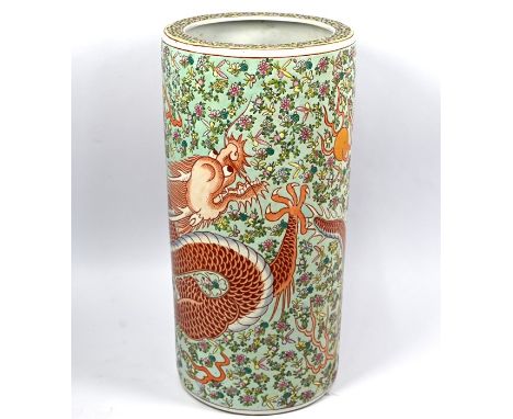 A 20th century Chinese cylindrical stick stand decorated with a single red dragon in pursuit of the flaming pearl surrounded 