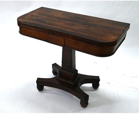 A Victorian rosewood card table, the fold over top swivel top raised on a tapering square support, to a quad form base on con