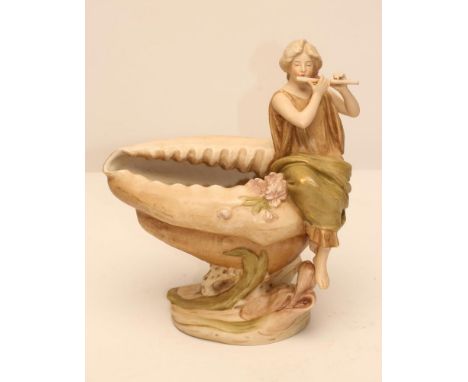 AN ART NOUVEAU ROYAL DUX BISQUE PORCELAIN FIGURAL CENTREPIECE modelled as a maiden playing a flute, seated on the edge of a l