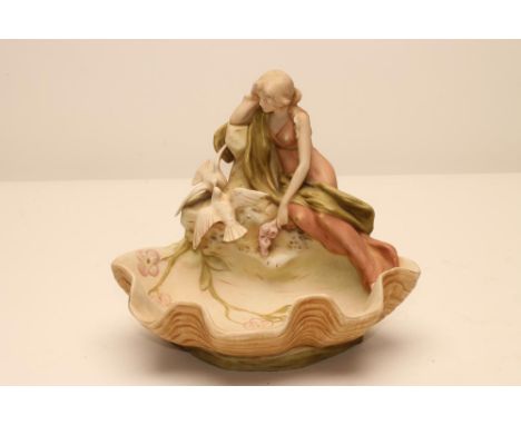 AN ART NOUVEAU ROYAL DUX BISQUE PORCELAIN FIGURAL CENTREPIECE, modelled as a young girl seated on the edge of a clam shell be