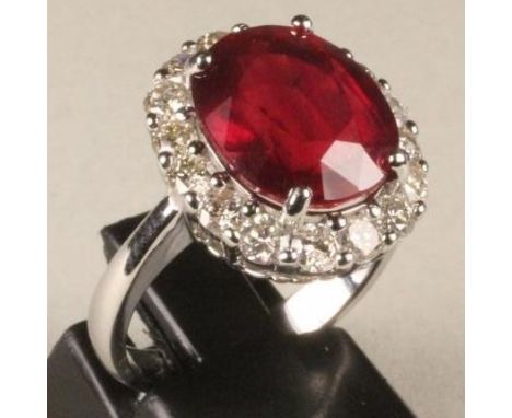 A RUBY AND DIAMOND CLUSTER RING, the oval facet cut ruby of approximately 7cts claw set to a border pave set with sixteen sma