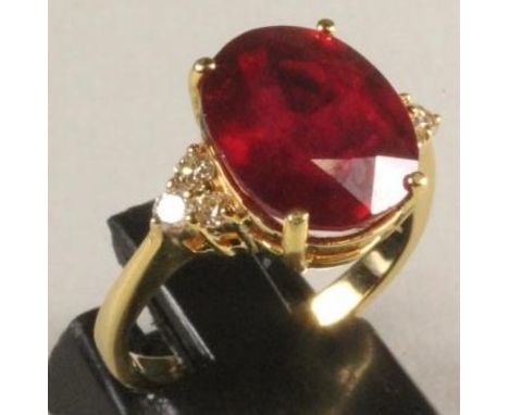 A RUBY RING, the oval facet cut stone of approximately 7cts, claw set to triangular shoulders each with three small round bri